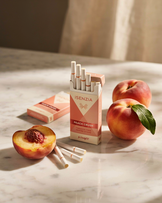ISENZIA peach crush cigarettes on a marble surface with peaches
